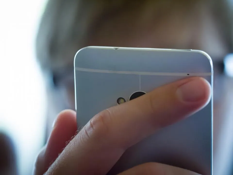 A hand holding a smartphone close to the face